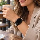 UrbanGleam — pulseira com relógio usada por uma mulher, num café. Imagem ilustrativa gerada por IA; relógio não incluído.